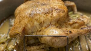 Chapon rôti doré dans un plat de cuisson, arrosé de son jus