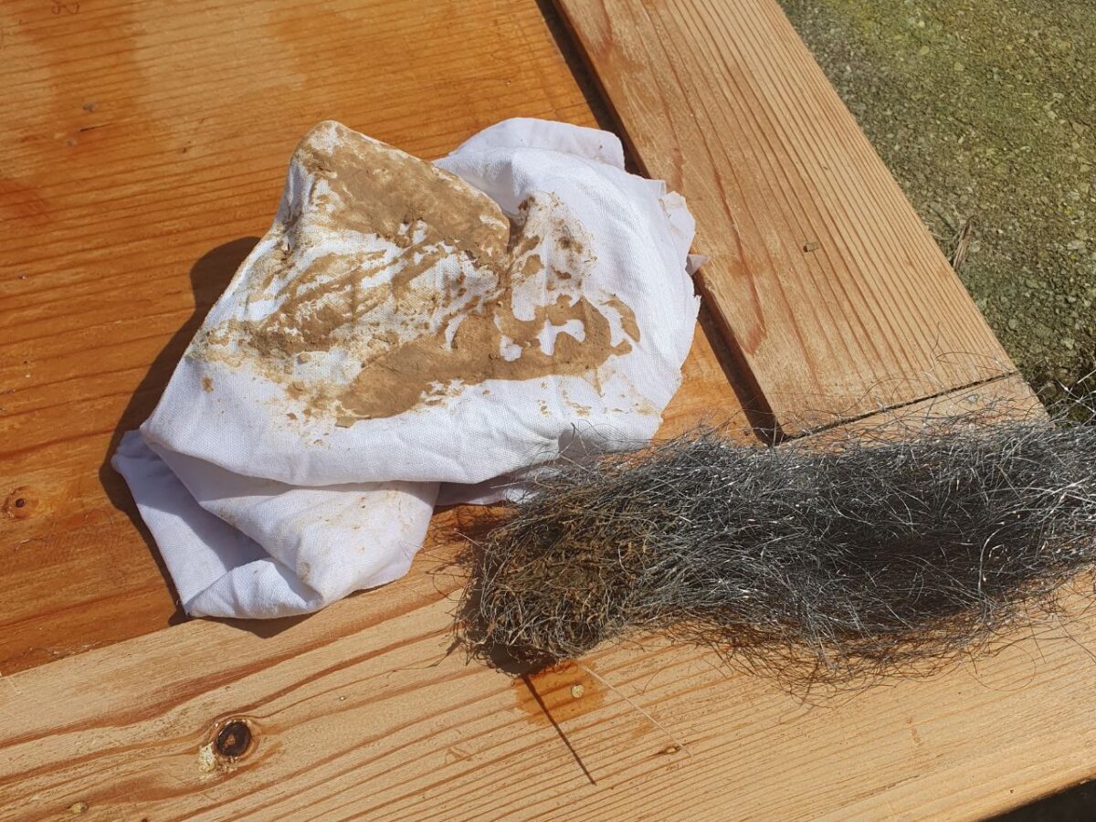 Meuble en bois en cours de peinture, pinceau et pot de sous-couche blanche posés sur une bâche